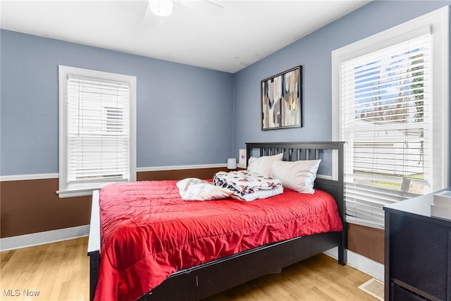 bedroom with multiple windows, ceiling fan, and light hardwood / wood-style floors