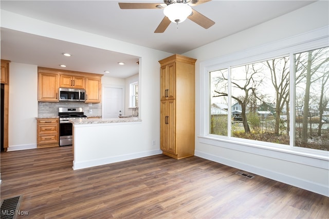 kitchen featuring dark hardwood / wood-style floors, light stone countertops, appliances with stainless steel finishes, and tasteful backsplash