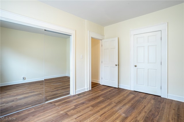 unfurnished bedroom featuring a closet and dark wood-type flooring