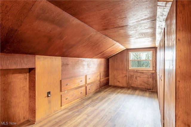 additional living space featuring light hardwood / wood-style floors, vaulted ceiling, wooden ceiling, and wood walls