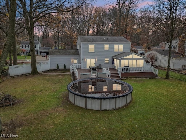 back house at dusk with a yard and a swimming pool side deck