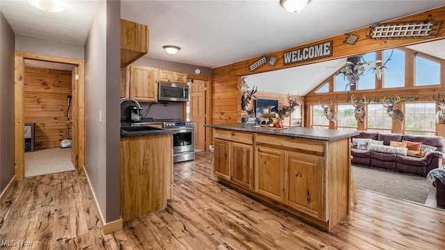 kitchen featuring wood walls, sink, vaulted ceiling, light wood-type flooring, and stainless steel appliances