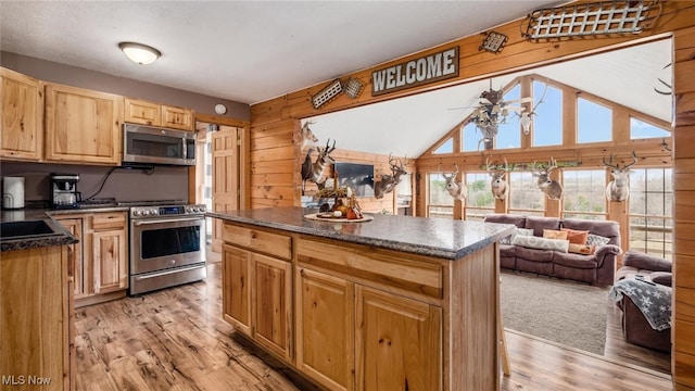 kitchen featuring wooden walls, ceiling fan, stainless steel appliances, and light wood-type flooring