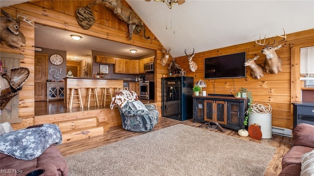 living room with high vaulted ceiling, wooden walls, and light hardwood / wood-style flooring