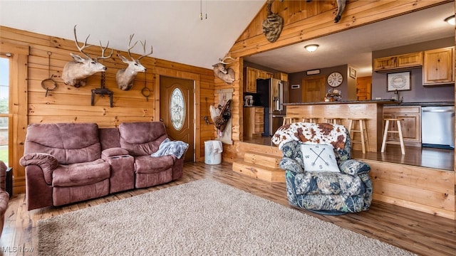 living room featuring wood walls, sink, lofted ceiling, and light wood-type flooring