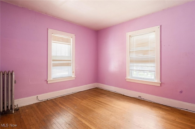 unfurnished room featuring radiator heating unit and hardwood / wood-style floors