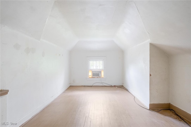 bonus room featuring cooling unit, light hardwood / wood-style floors, and lofted ceiling