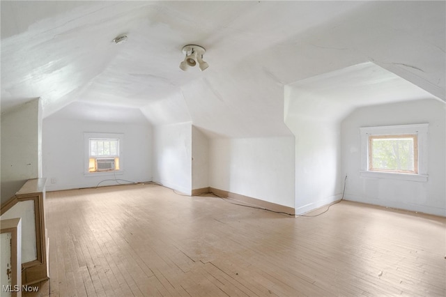 additional living space with lofted ceiling, cooling unit, and light wood-type flooring