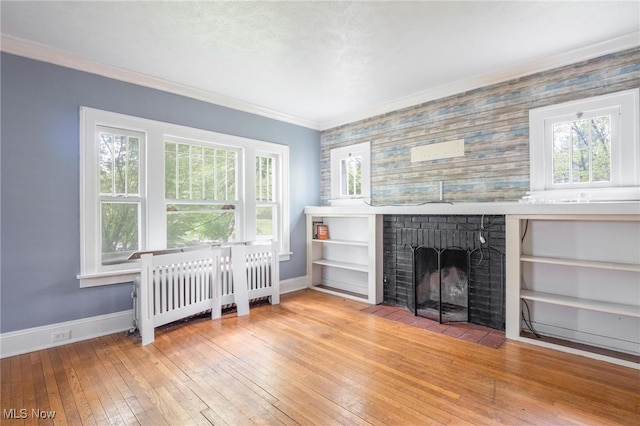 unfurnished living room with radiator, crown molding, light hardwood / wood-style flooring, and a fireplace