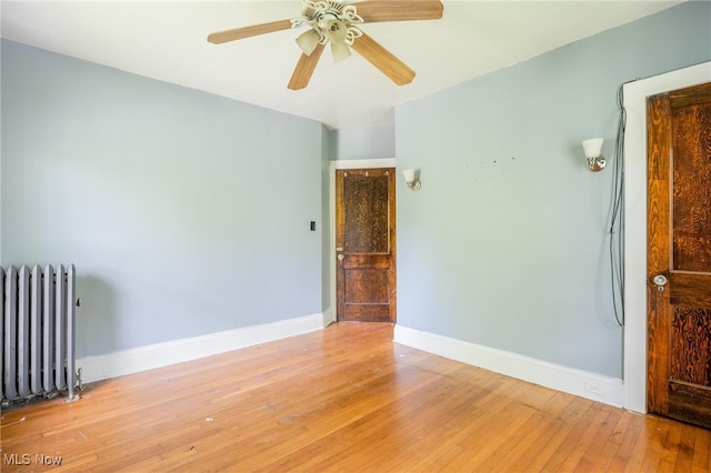 spare room with radiator, ceiling fan, and light hardwood / wood-style floors