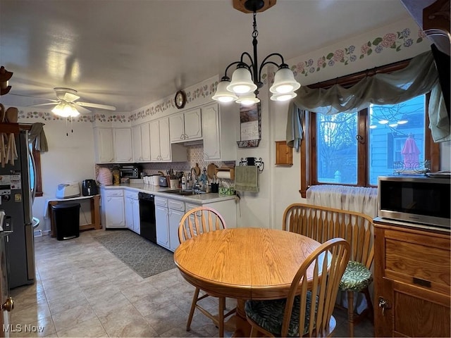 kitchen with appliances with stainless steel finishes, a sink, light countertops, a ceiling fan, and a chandelier