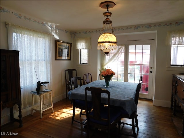 dining area with hardwood / wood-style floors, a wealth of natural light, and a notable chandelier