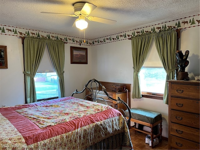 bedroom with ceiling fan, parquet floors, and a textured ceiling