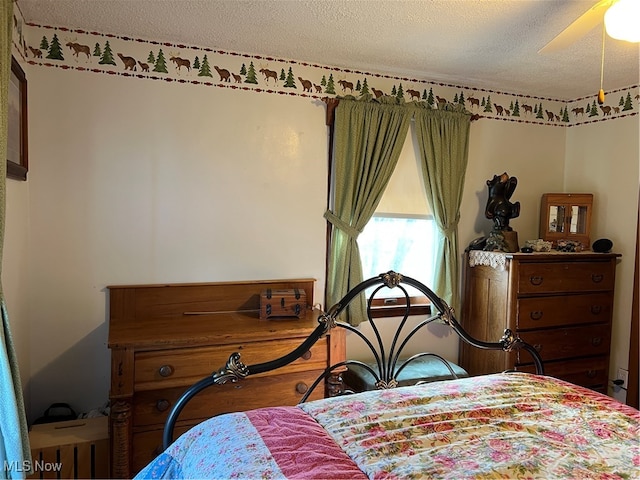 bedroom with hardwood / wood-style flooring, ceiling fan, and a textured ceiling