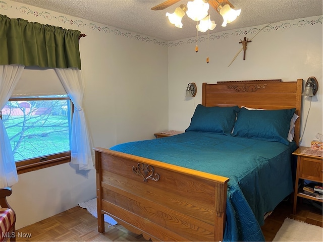 bedroom featuring ceiling fan, a textured ceiling, and parquet flooring