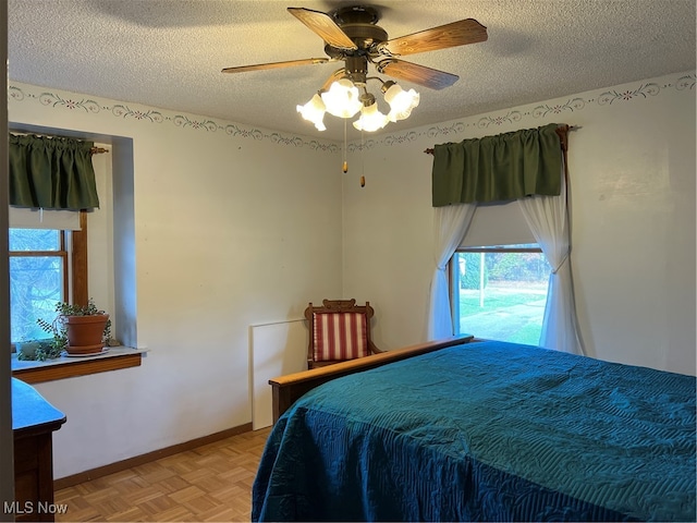 bedroom featuring ceiling fan, light parquet flooring, and a textured ceiling