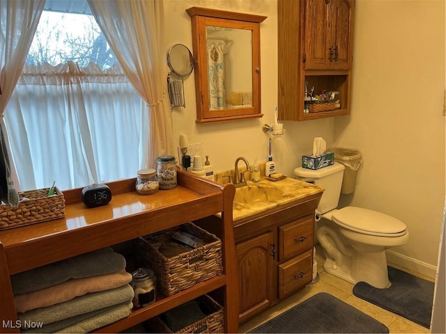 bathroom with toilet, vanity, and tile patterned flooring