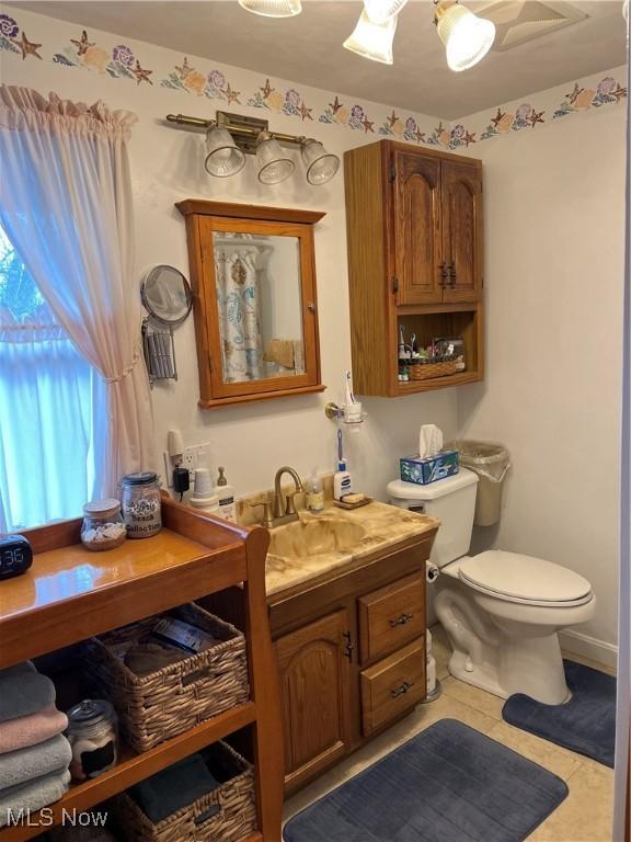 bathroom with toilet, vanity, and tile patterned floors
