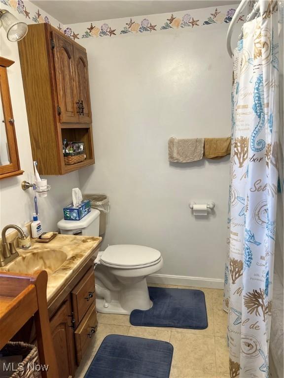 bathroom featuring toilet, vanity, tile patterned flooring, baseboards, and a shower with curtain
