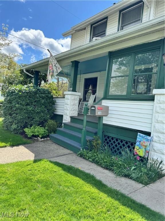 doorway to property featuring a porch and a lawn