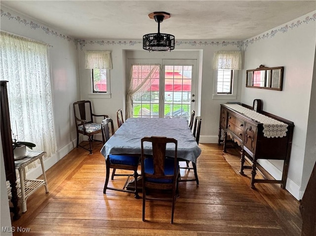 dining space featuring a chandelier, hardwood / wood-style flooring, and baseboards