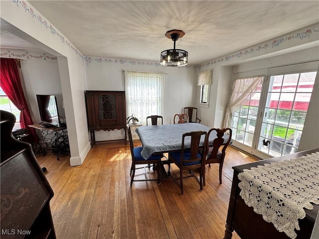 dining space with healthy amount of natural light, light wood-type flooring, and a chandelier