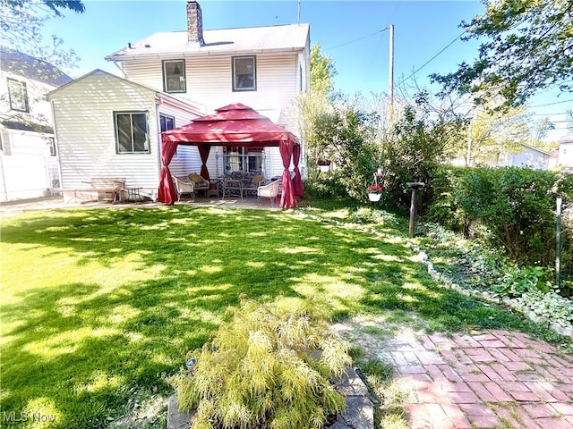 rear view of house featuring a patio area, a gazebo, and a chimney