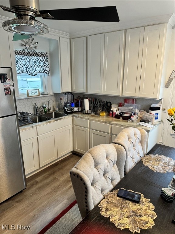 kitchen with stainless steel fridge, tasteful backsplash, ceiling fan, hardwood / wood-style flooring, and white cabinetry