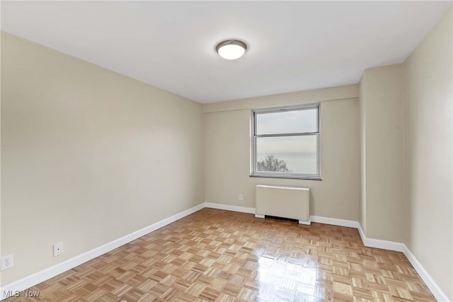 spare room with radiator and light parquet floors