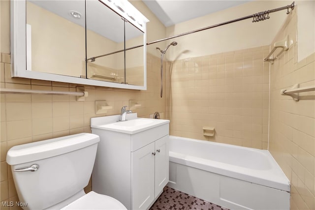 full bathroom featuring vanity, toilet, tile walls, and tiled shower / bath combo