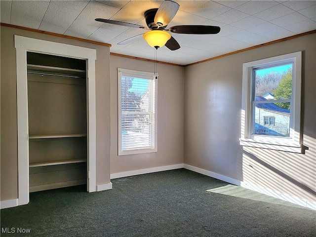 unfurnished bedroom with dark colored carpet, ceiling fan, a closet, and multiple windows