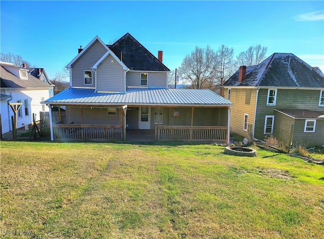 back of house featuring covered porch, a yard, and a fire pit