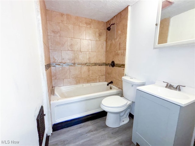 full bathroom featuring tiled shower / bath combo, a textured ceiling, toilet, vanity, and hardwood / wood-style flooring