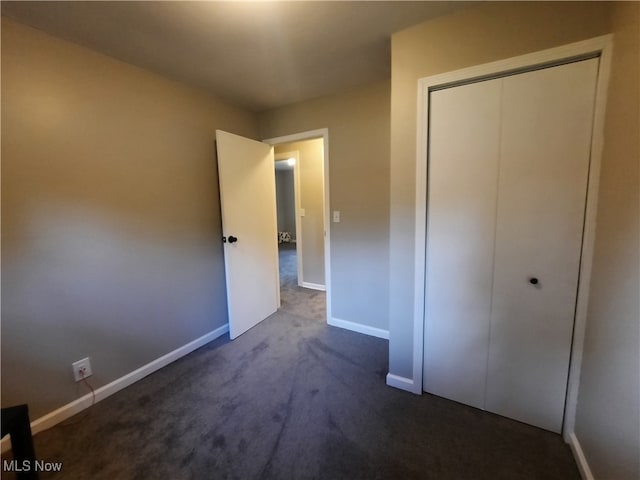 unfurnished bedroom with dark colored carpet and a closet