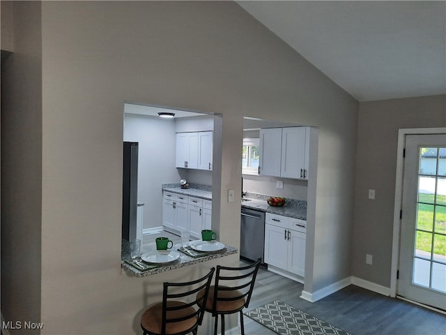 kitchen featuring light stone countertops, appliances with stainless steel finishes, vaulted ceiling, dark wood-type flooring, and white cabinets