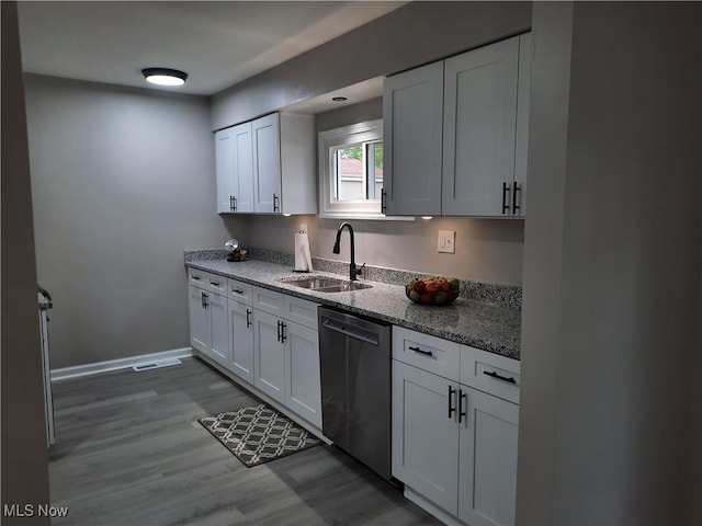 kitchen with sink, stainless steel dishwasher, dark hardwood / wood-style floors, light stone countertops, and white cabinetry