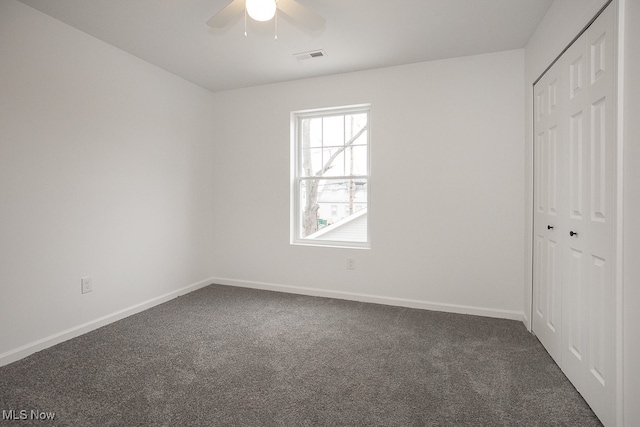 unfurnished bedroom with dark colored carpet, ceiling fan, and a closet