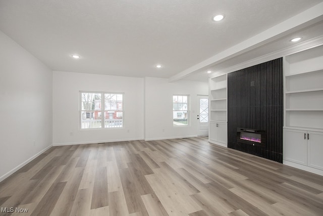 unfurnished living room with plenty of natural light, a large fireplace, and light hardwood / wood-style flooring