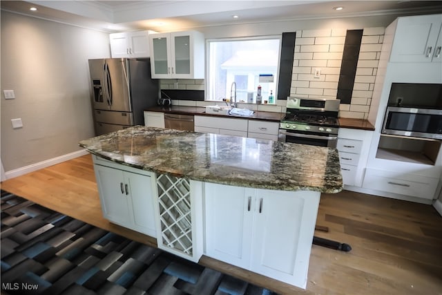 kitchen with tasteful backsplash, white cabinetry, a kitchen island, and appliances with stainless steel finishes