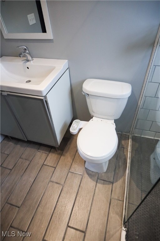 bathroom with wood-type flooring, vanity, and toilet