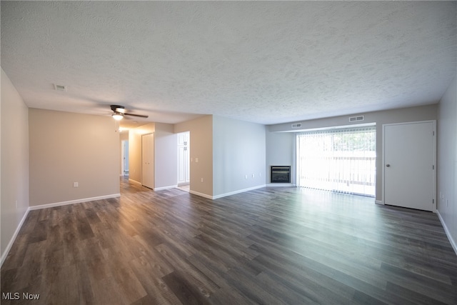 unfurnished living room with a textured ceiling, ceiling fan, and dark wood-type flooring