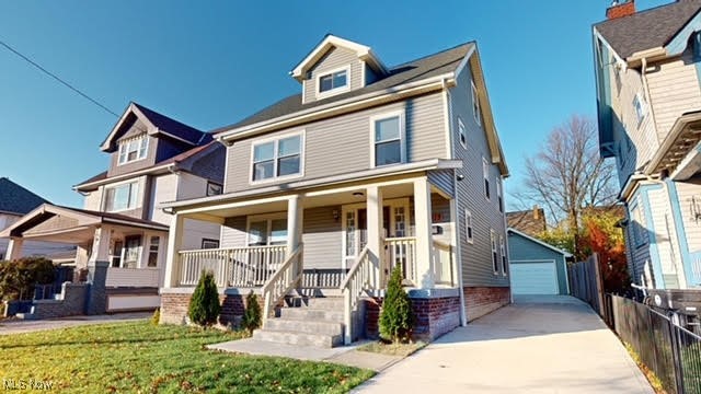 view of front of home featuring covered porch, an outbuilding, a garage, and a front lawn