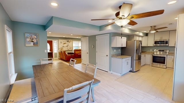 kitchen with appliances with stainless steel finishes, light hardwood / wood-style flooring, white cabinetry, and ceiling fan