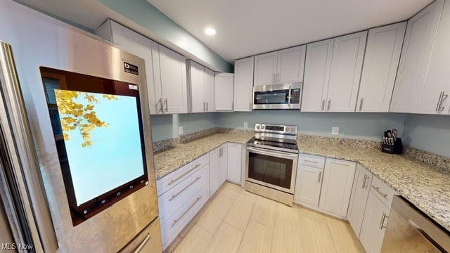 kitchen featuring white cabinets, appliances with stainless steel finishes, and light stone counters