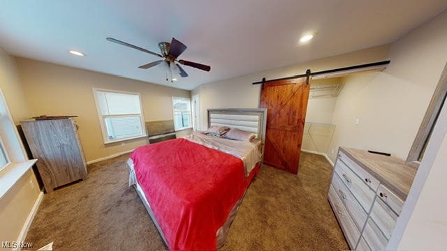 carpeted bedroom with a barn door and ceiling fan