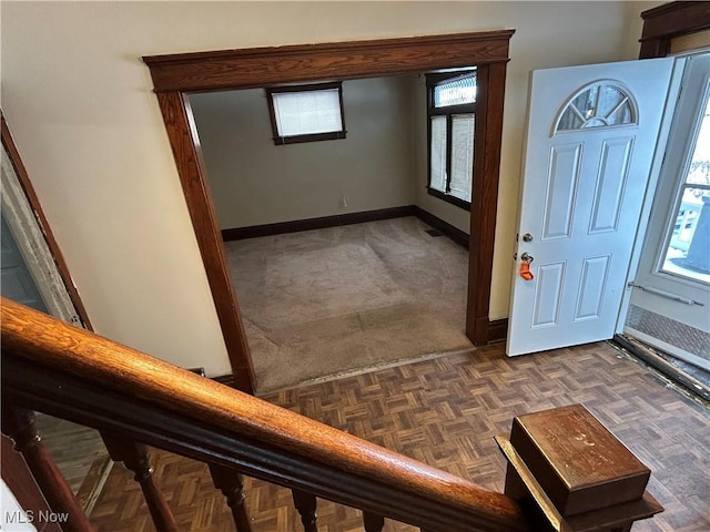 foyer entrance with dark parquet flooring and a healthy amount of sunlight