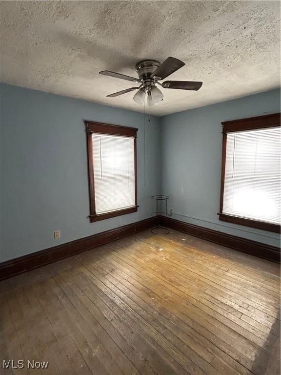 spare room featuring hardwood / wood-style flooring, a textured ceiling, and ceiling fan