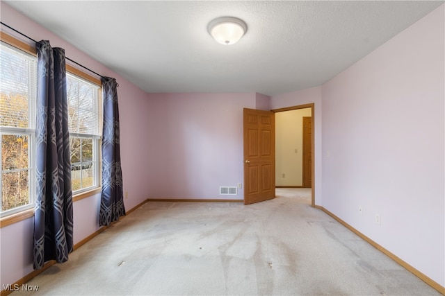 spare room with light colored carpet and a textured ceiling