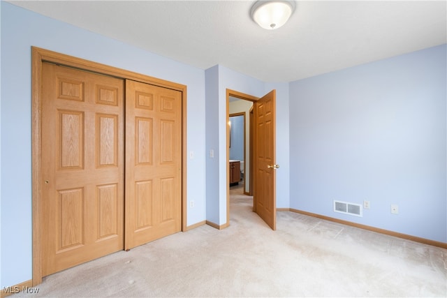 unfurnished bedroom featuring light colored carpet and a closet