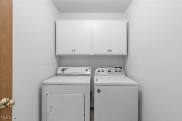 clothes washing area featuring washer and clothes dryer and cabinets